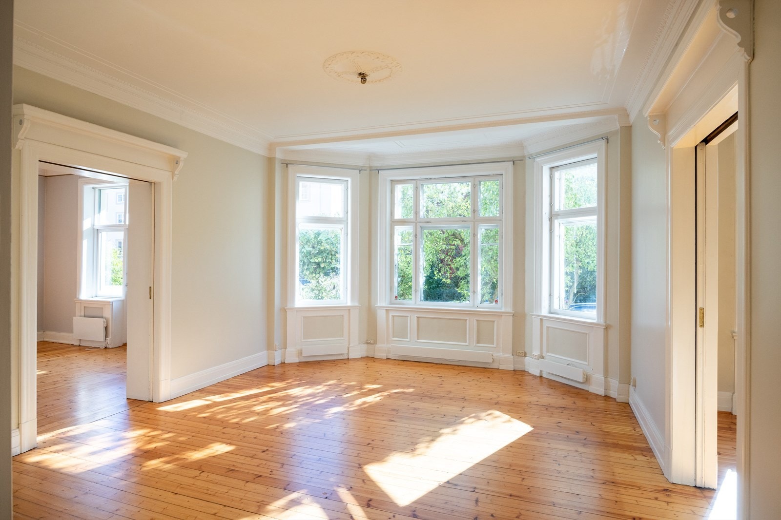 - Leiligheten har tre lyse stuer på rad med frodige trær utenfor - Galleribilde