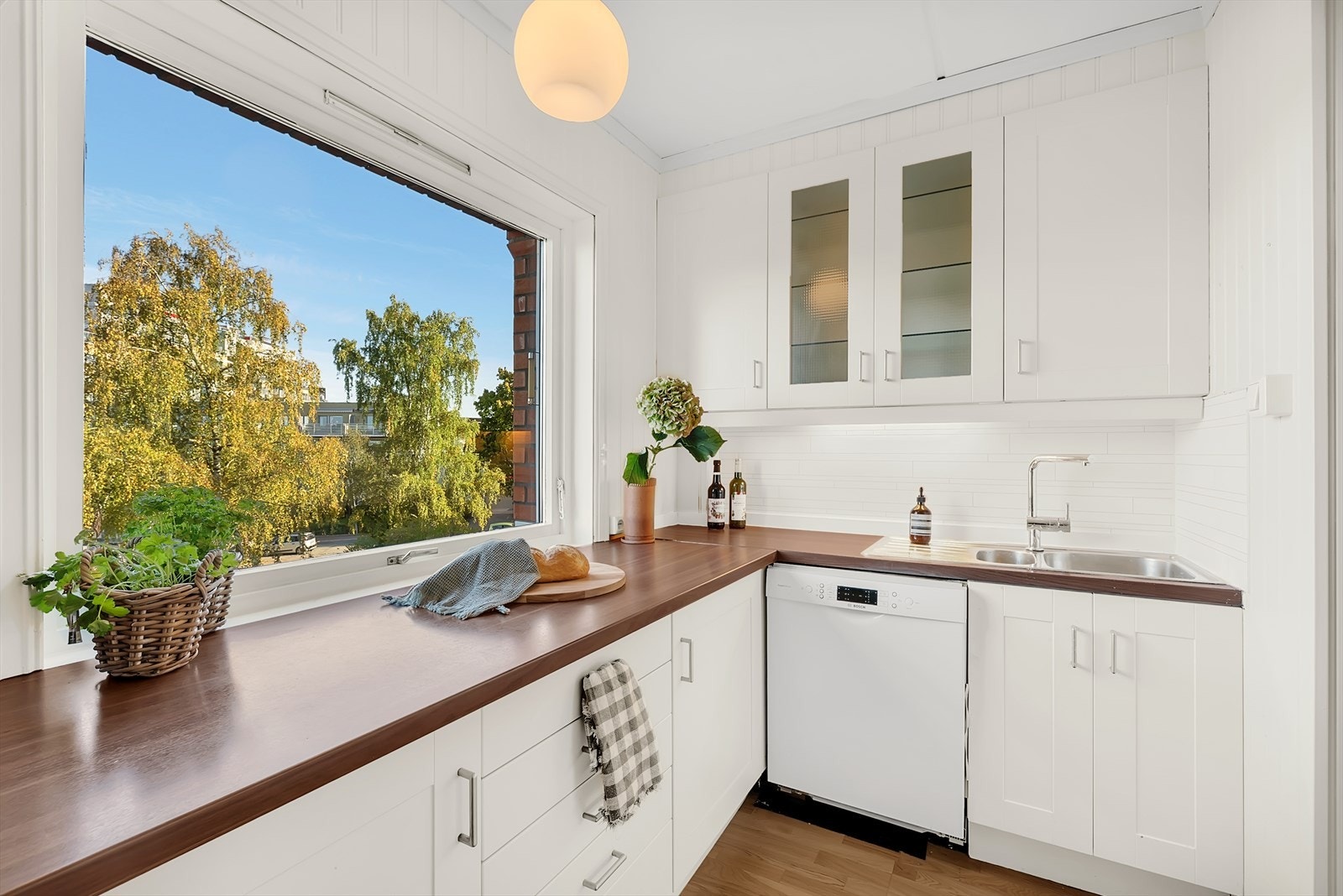 Kjøkken med parkett på gulv, tapet og malt mdf panel på vegger samt malt tak. Galleribilde