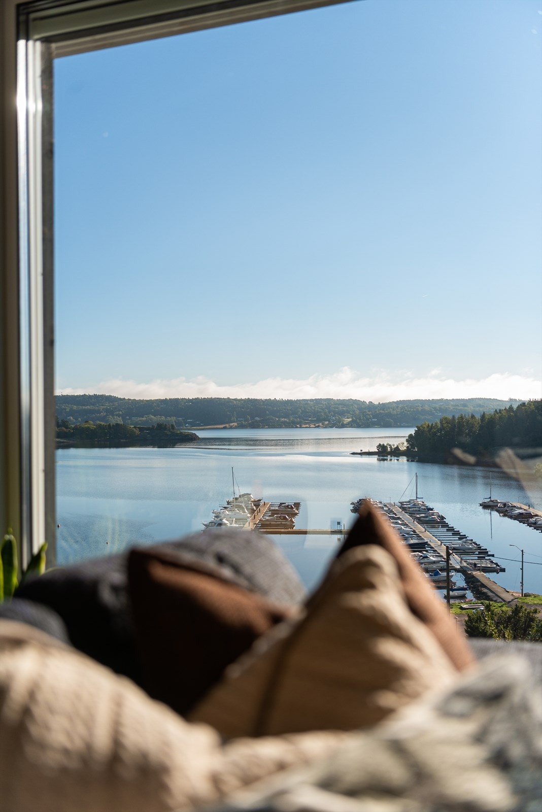 En lekker, romslig og delikat stue i lyse farger med store vindusflater som slipper sjøen rett inn. Galleribilde
