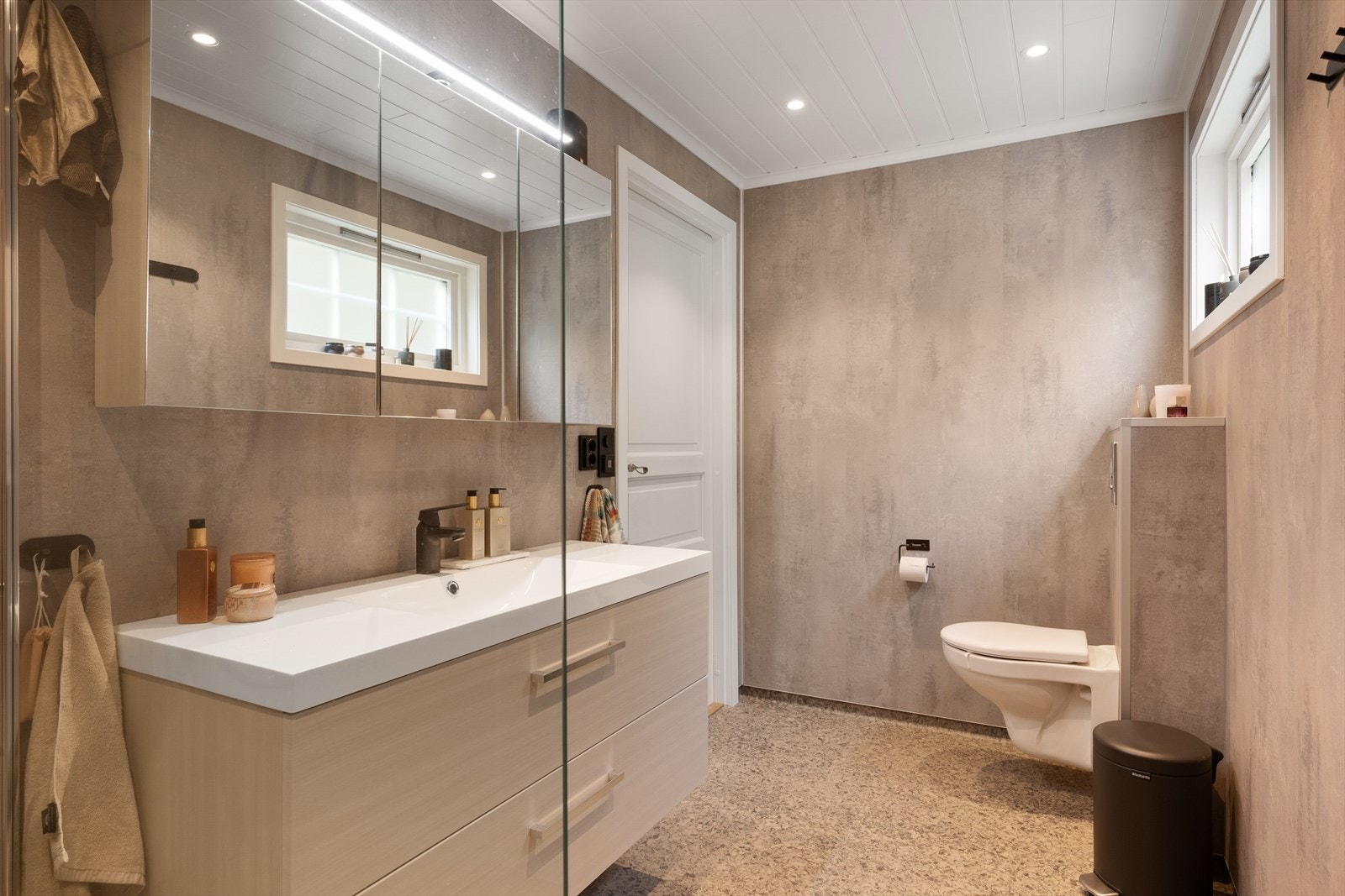 Badet er innredet med dusjvegger, innebygd toalett og baderomsinnredning med servant. Galleribilde