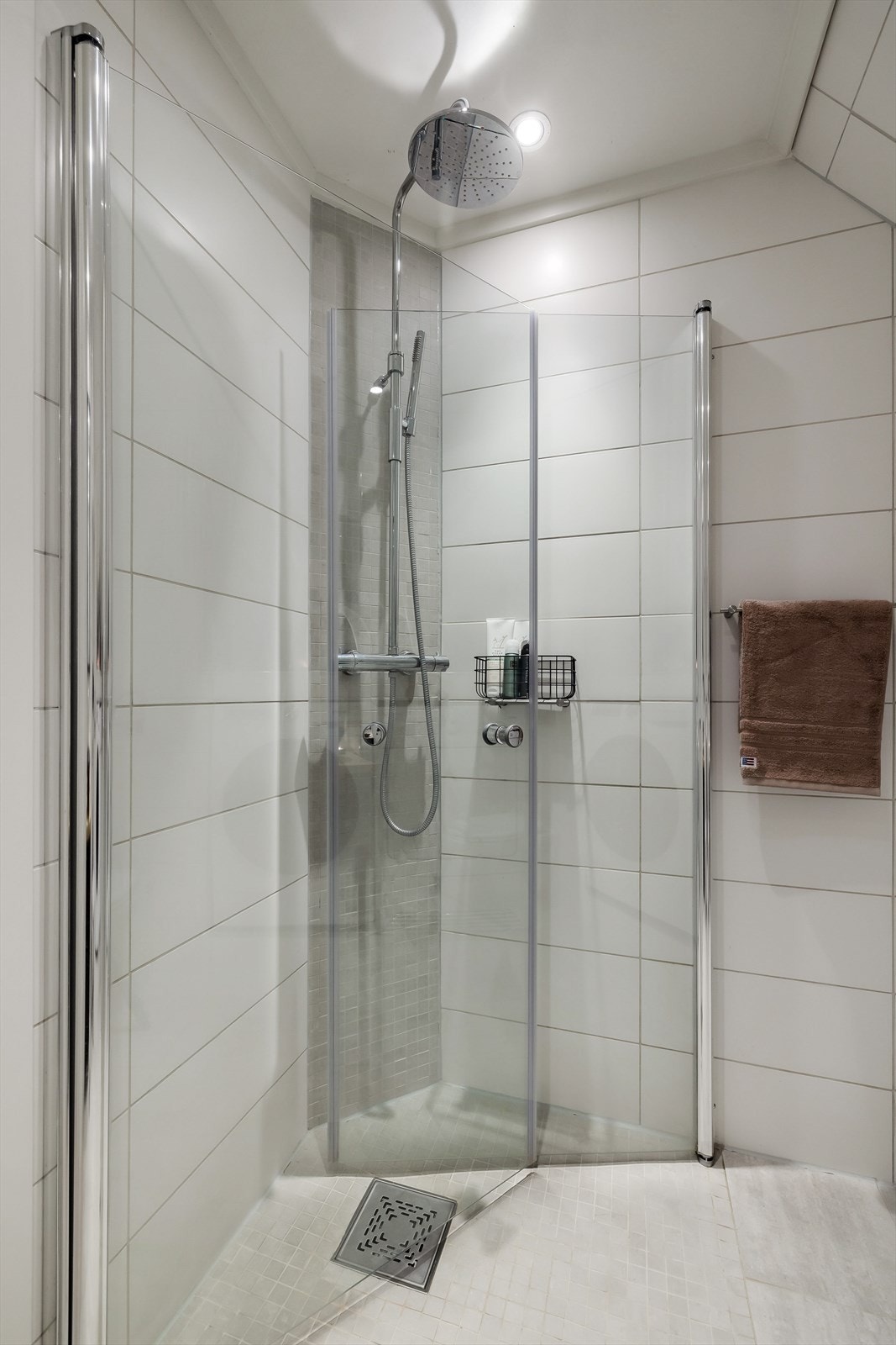 Badet er utstyrt med veggmontert wc, dusjhjørne med innfellbare dusjdører, servantbolle over heltre benkeplate. Galleribilde