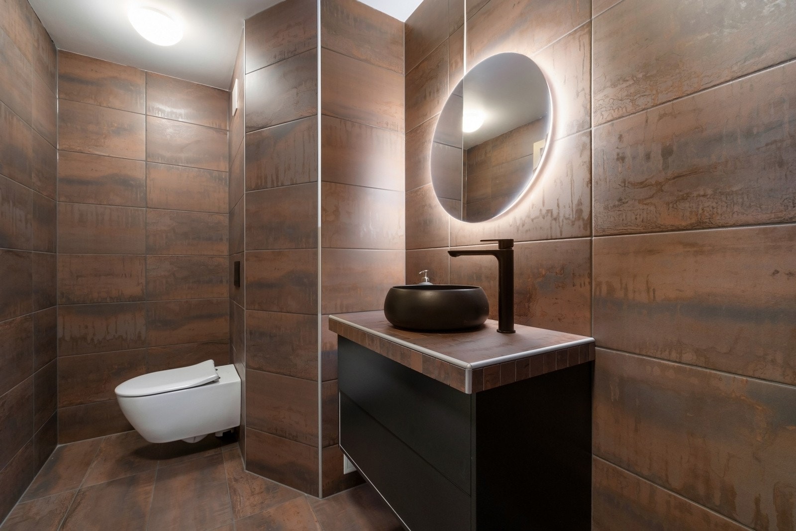 Innredningen inkluderer veggfestet klosett med innebygd sisterne, servant og benkeskap med glatte fronter. Et speil med belysning over servanten gir et moderne preg. Galleribilde