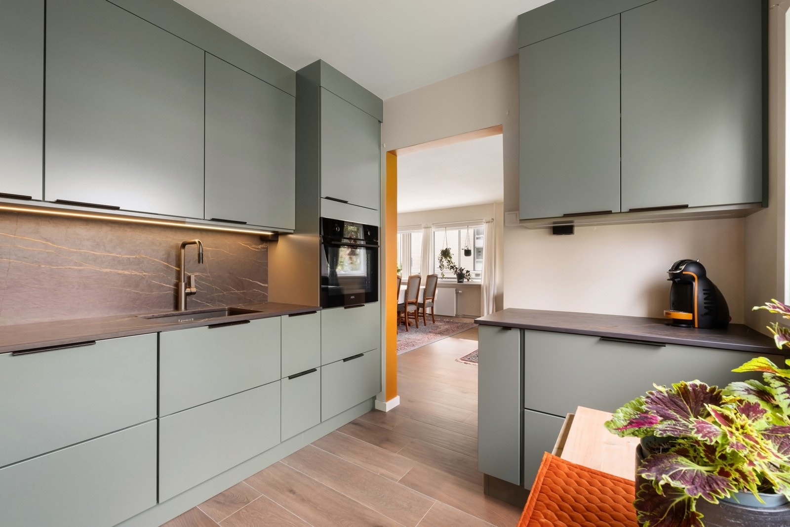 Stilrent og moderne kjøkken fra Strai, nytt i 2022. Innredningen har glatte fronter og en elegant benkeplate samt backsplash i kompositt. Den nedfelte vasken i sort kompositt gir et tidløst preg. Galleribilde