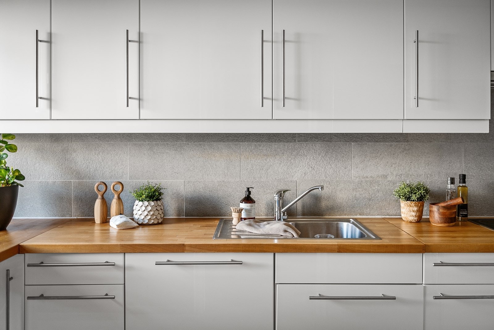 Enkel oppvaskkum med benkebeslag, ventilator og innfelte hvitevare som koketopp, stekeovn, oppvaskmaskin, frittstående kjøleskap. Galleribilde