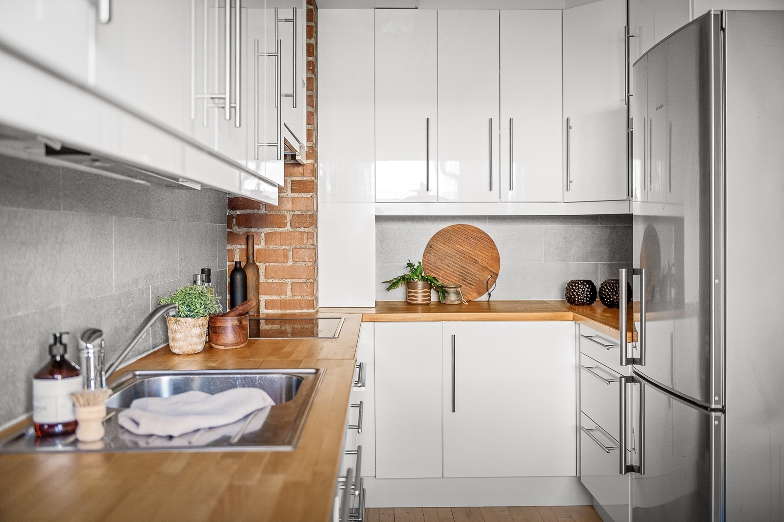 Ikea kjøkkeninnredning med glatte høyglans skapfronter, heltre benkeplate med fliser på bakvegg. Galleribilde