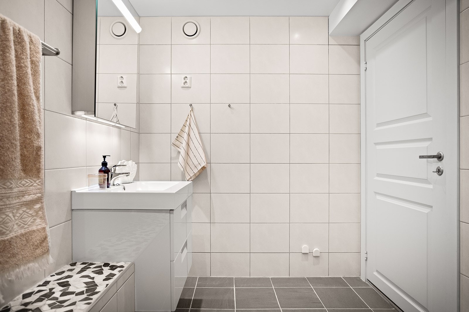 Opplyst pusset opp i 2012. Overflater er belagt med senket, malt gipshimling med innfelte downlights og flislagte veggflater. Galleribilde