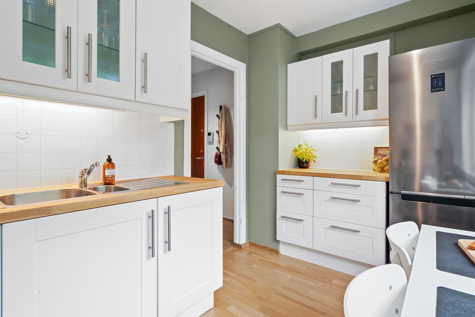 Over benken er det hvite flisplater og godt arbeidslys. Et frittstående kjøleskap får plass på enden. Galleribilde