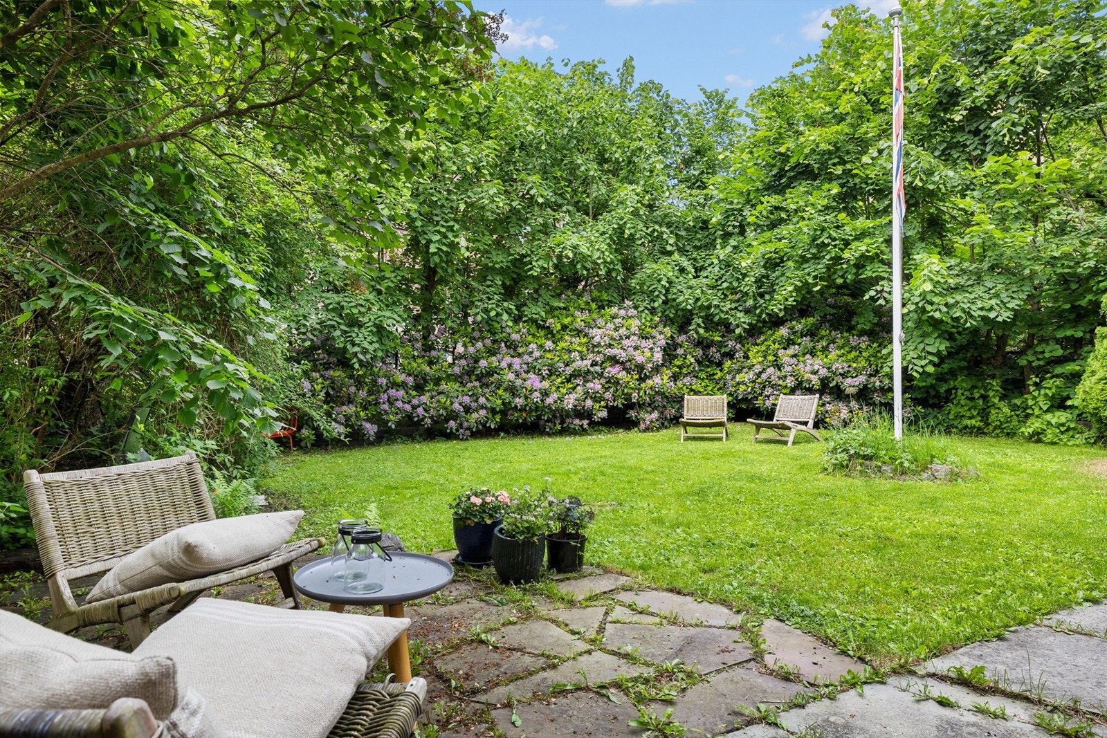 Usjenert hage med flott beplantning og blomstrende Rododendron. Galleribilde