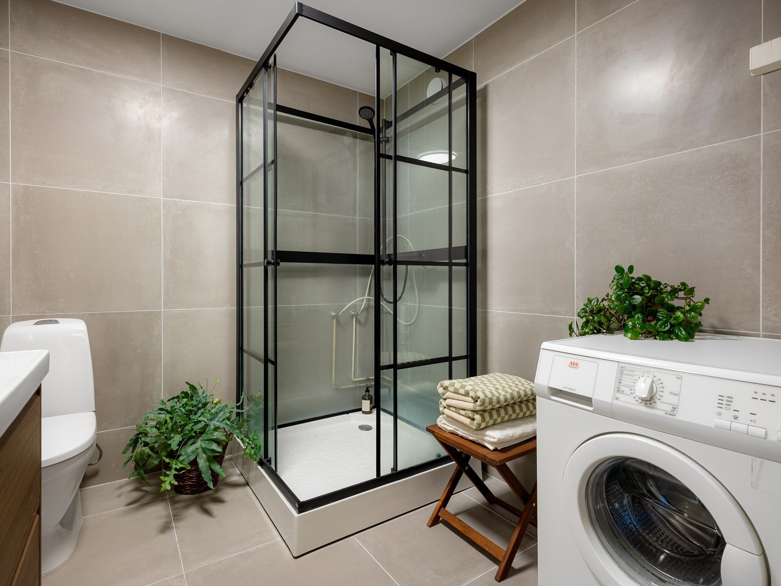 Badet er innredet med toalett, dusjkabinett og moderne baderomsinnredning med servant nedfelt i innredning og speil Galleribilde