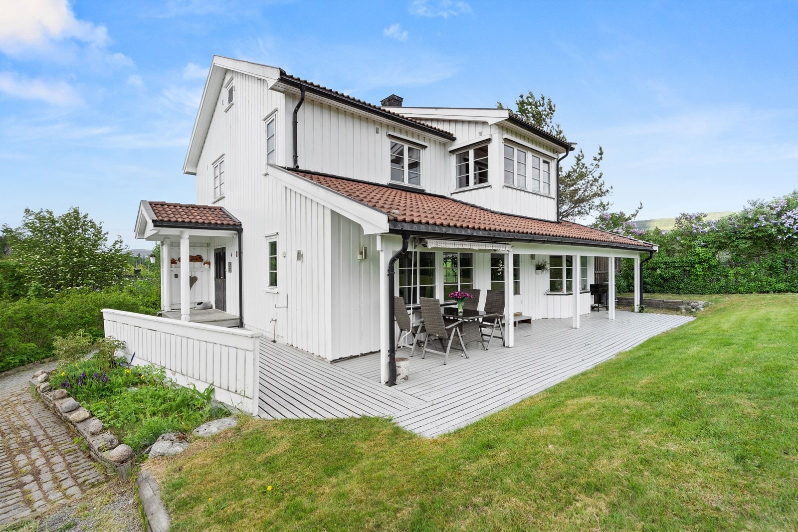 Rundt sør- og vestsiden av boligen kan sommerdagene tilbringes på en delvis overbygd markterrasse. Galleribilde