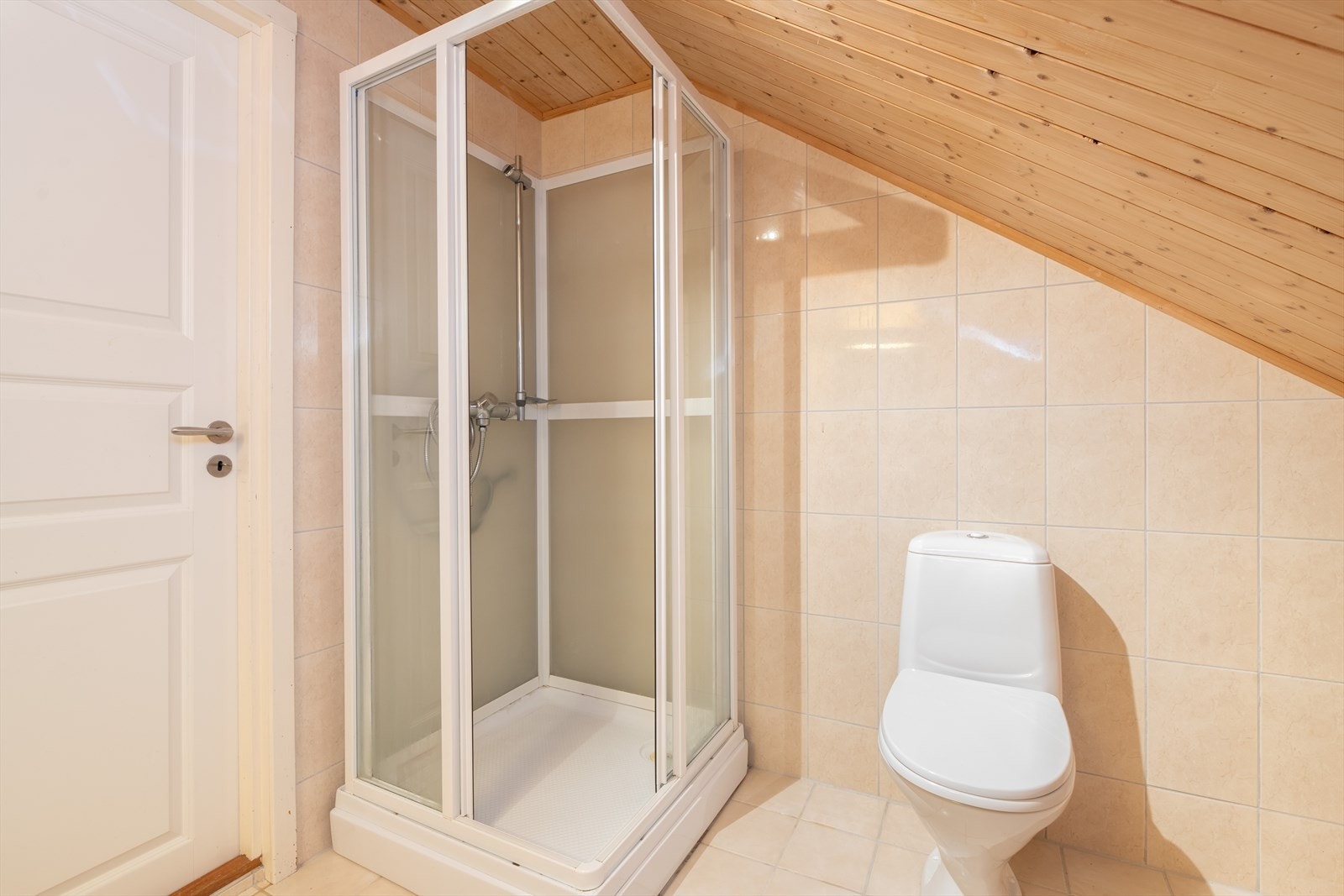 Badet er for øvrig utstyrt med gulvmontert toalett og dusjkabinett, samt en mindre varmtvannstank. Flis på gulv, samt flis og panel på vegger. Galleribilde