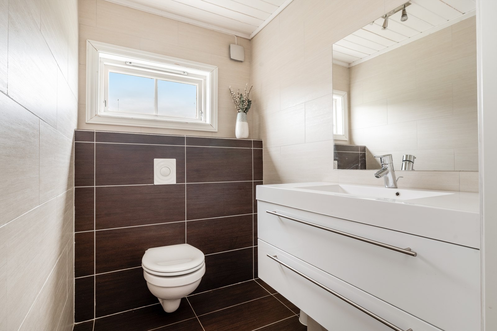 Toalettrommet er utstyrt med veggmontert toalett og romslig servantinnredning med skuffer og heldekkende servantplate. Speil på vegg. Galleribilde