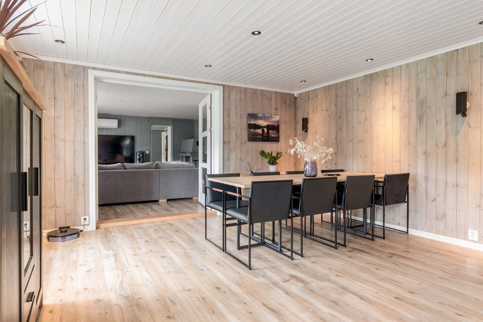 Overflater består av pen laminat på gulv og flott panel på vegger, samt hvitmalt panel med innfelte downlights i tak. Vegg ved ildsted er kledd i flott steinpanel. Galleribilde