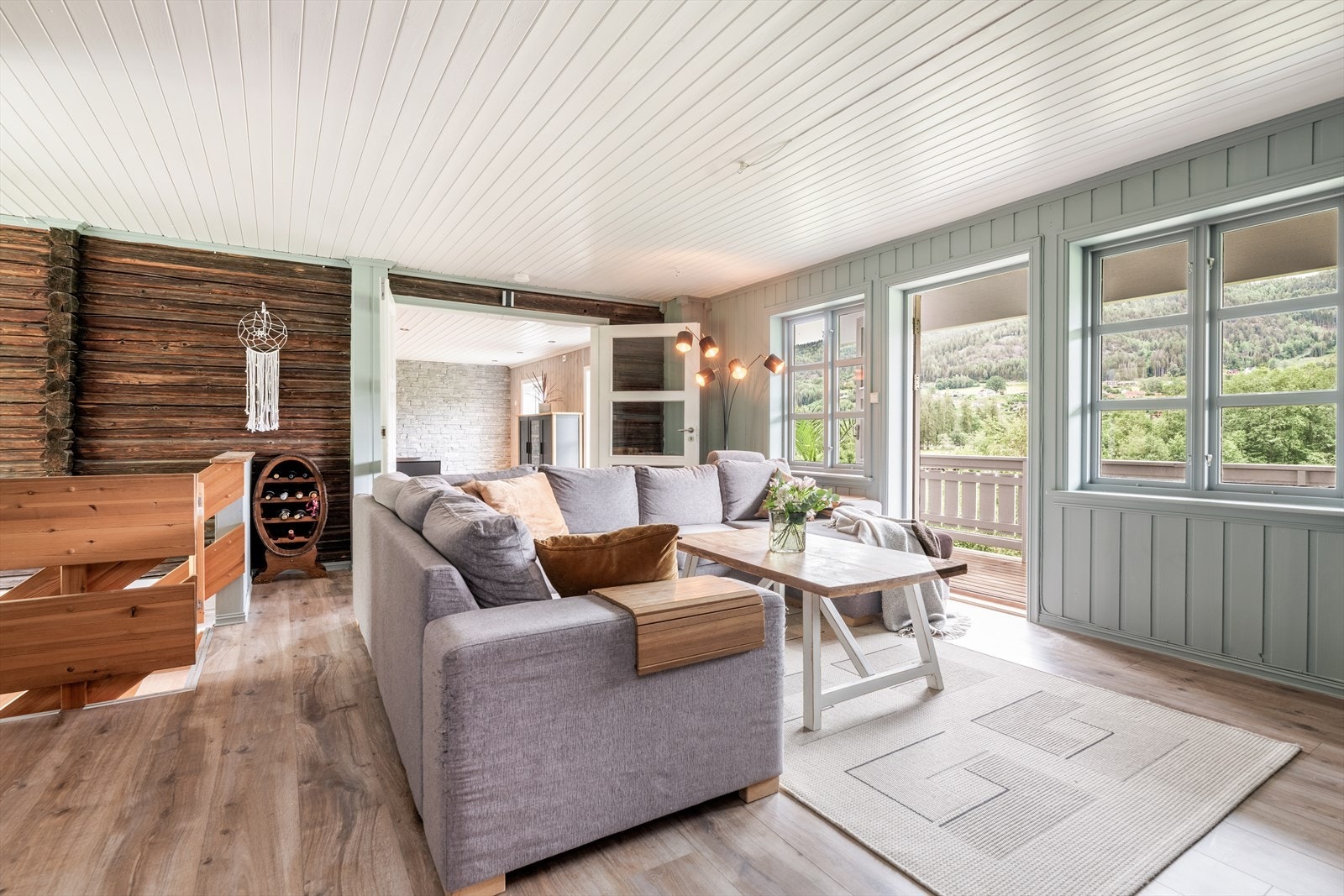 I stuen er det etablert åpen peis og nedgang til underetasjen via furutrapp. Legg merke til den sjarmerende, eldre tømmerveggen mot spisestuen! Galleribilde