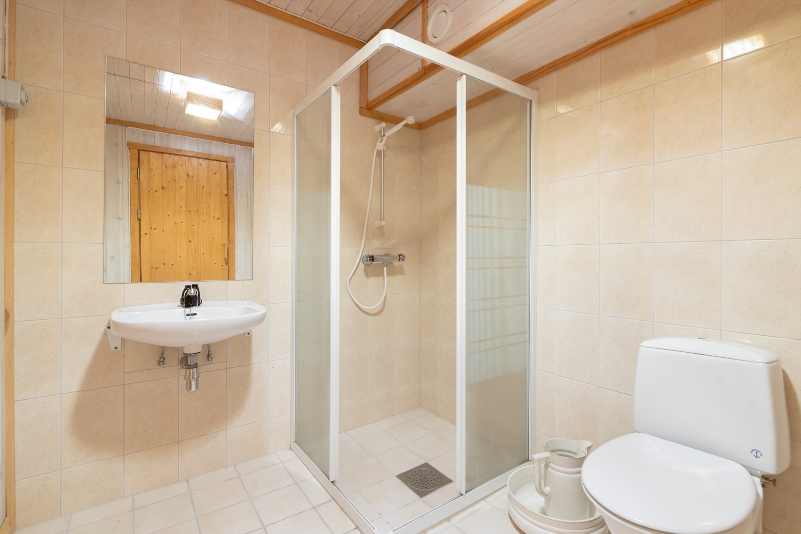 Badet i underetasjen innehar standard fra 1990 og er utstyrt med gulvmontert toalett, åpen dusjløsning med dusjdører og vegghengt servant. Galleribilde