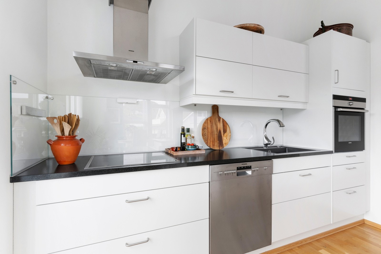 Mellom benkeplate og overskap og ved kokesonen er det glassplate som gjør det enkelt å holde rent. Galleribilde