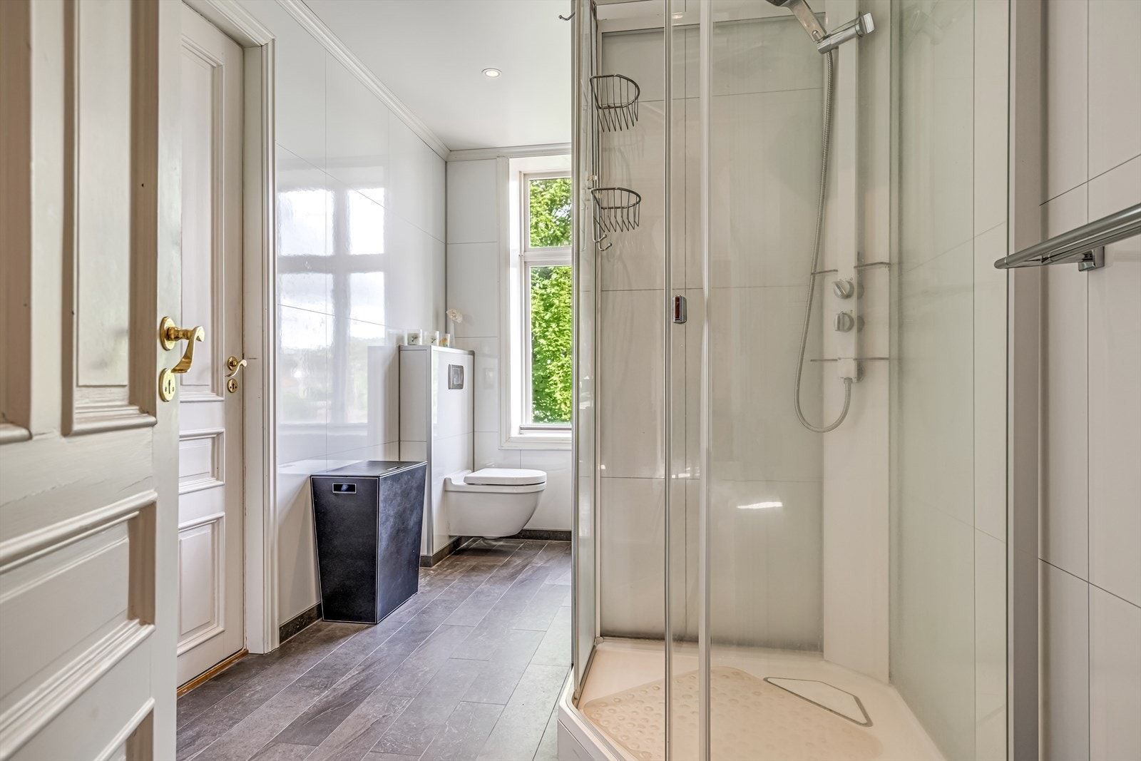 Badet har innredning med nedfelt servant, veggmontert toalett og dusjkabinett Galleribilde