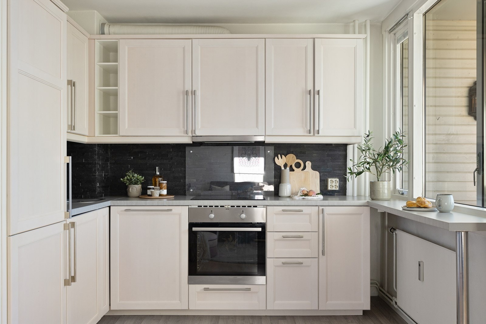 Lyst kjøkken med profilert innredning. Integrerte hvitevarer som kjøl/frys. stekeovn, induksjonstopp og ventilator medfølger salget. Galleribilde