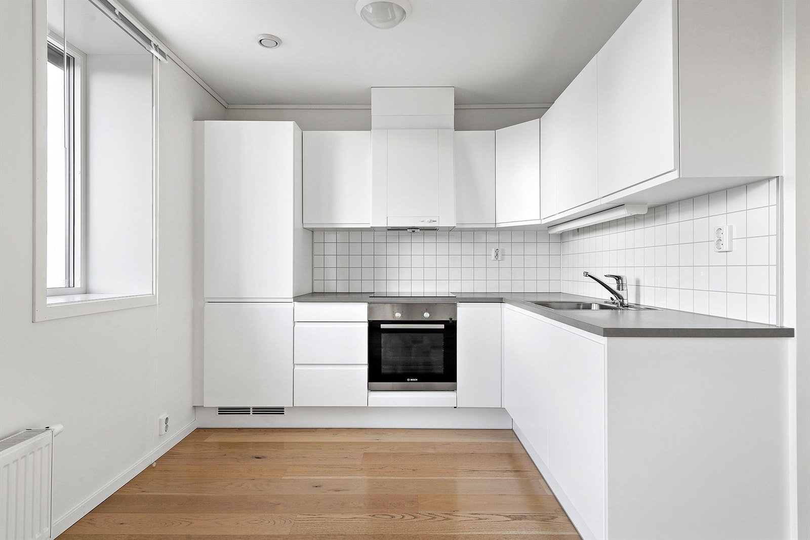 Hvit kjøkkeninnredning med underskap/skuffer og overskap, glatte folierte fronter. Galleribilde