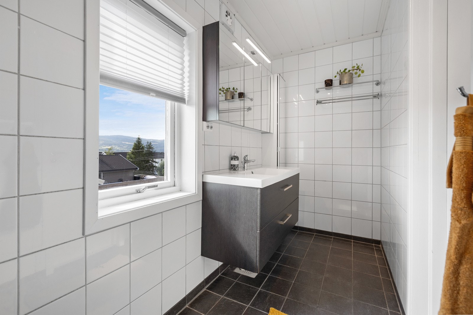 Fint bad med flislagte oveflater. Innredning med speil og belysning. Galleribilde