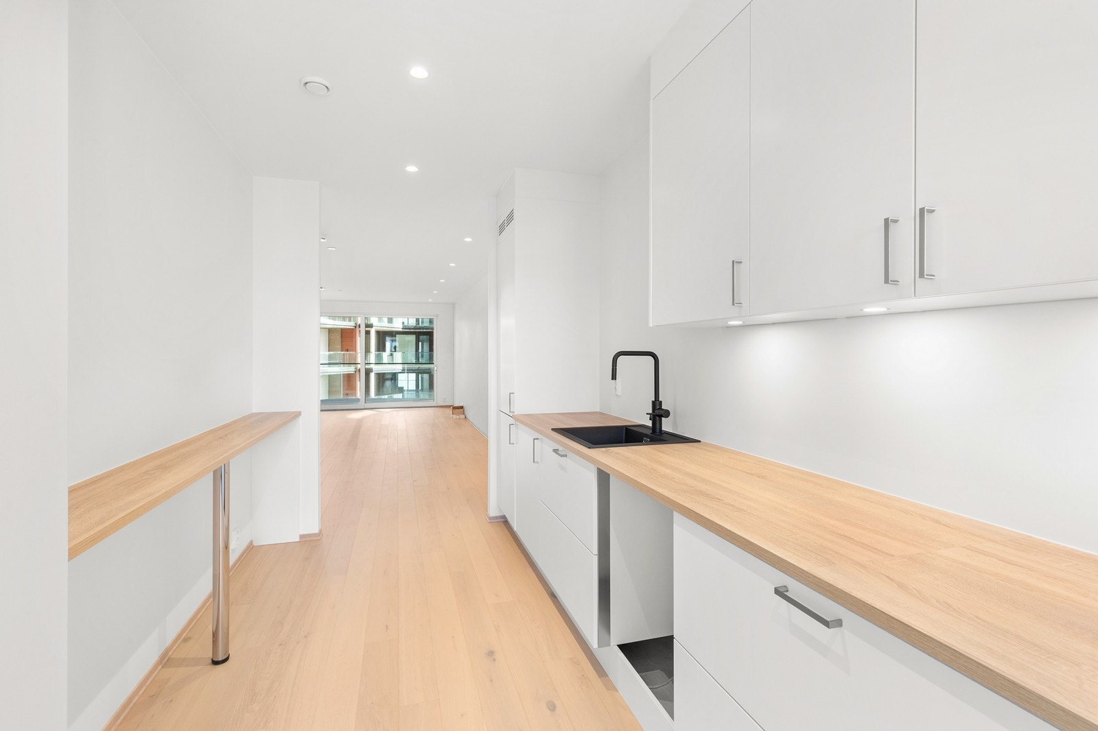 Pent kjøkken med høye overskap, matt svart armatur fra Tapwell og god benkeplass. Galleribilde