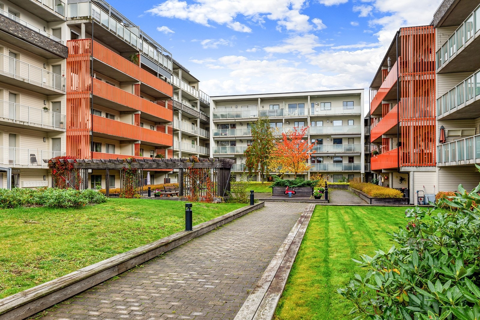 Felles uteområde er opparbeidet med gressplen, beplantning, steinbelagte internveier, lekeplass og sittebenker Galleribilde