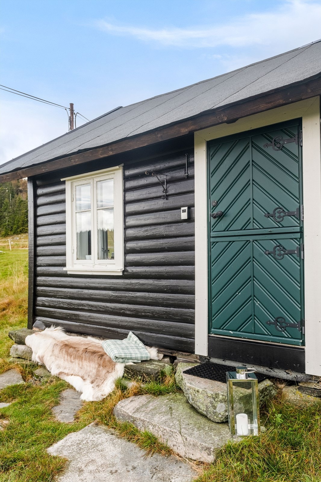 Ytterdøren er en pen, fabrikkmalt stalldør fra 2016. Ved inngangspartiet er det tillaget en hyggelig benk langs hytteveggen. Galleribilde
