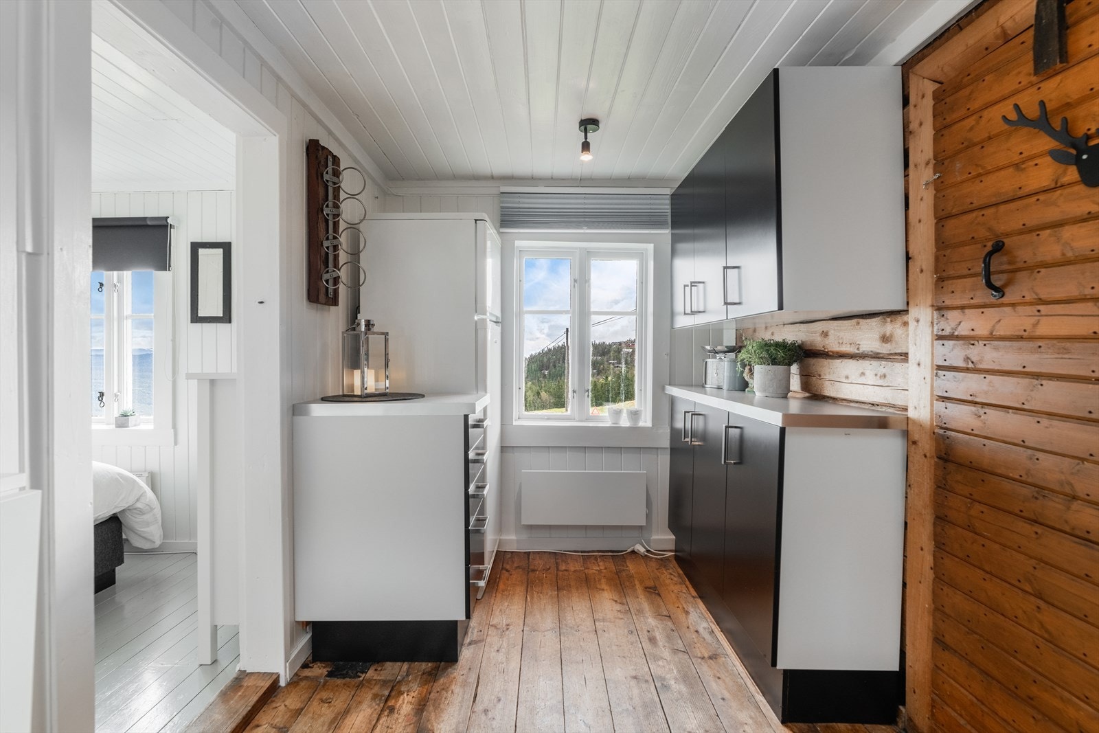 Kjøkkenet har for øvrig en koselig, eldre koieovn og et praktisk, veggmontert klaffebord. Flott tømmervegg mot stuen. Galleribilde