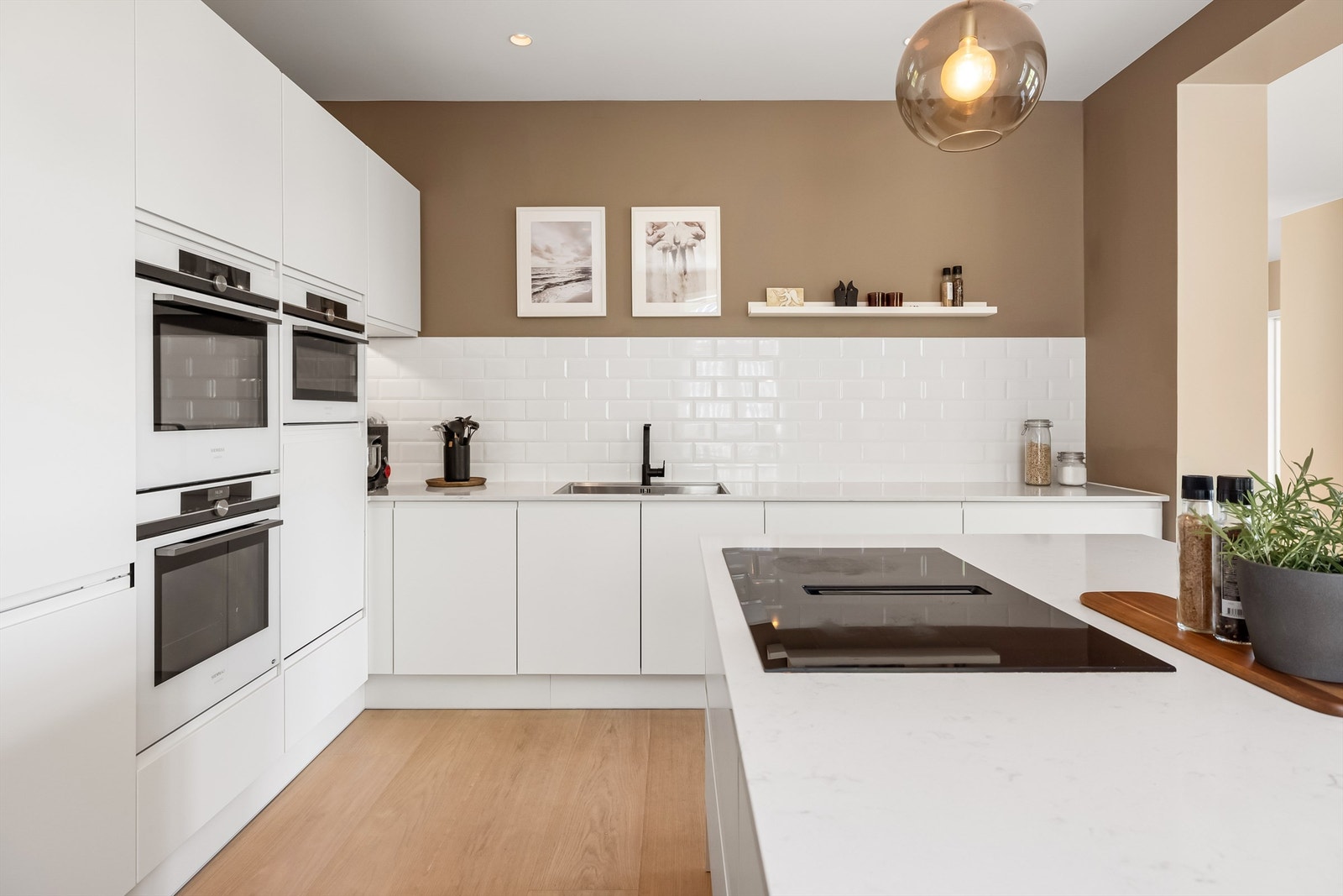 Lekkert veltilpasset kjøkken med glatte fronter. Benkeplate med nedfelt vask. Flotte fliser over benkeplate ved vask. Galleribilde