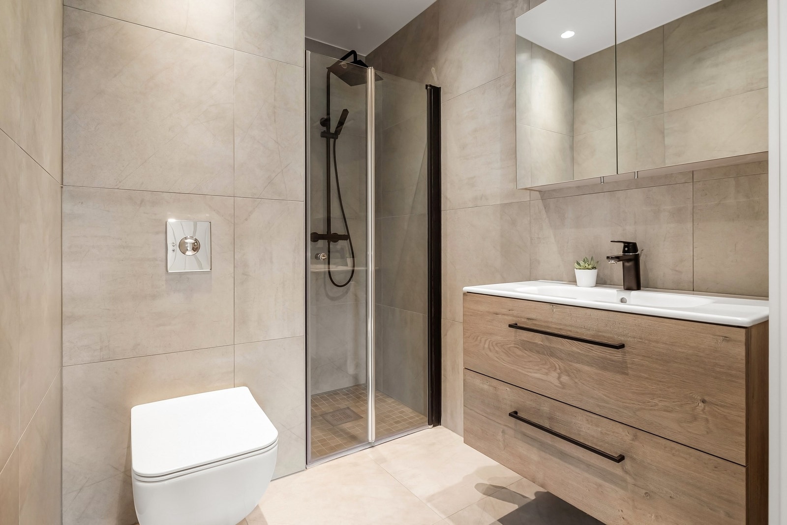 Helfliset bad/wc fra 2020. Meget pene fliser på både gulv og vegger. Flott baderomsmøblement med helstøpt servant og sort blandebatteri ved servant og i dusjnisje. Vegghengt toalett. Galleribilde