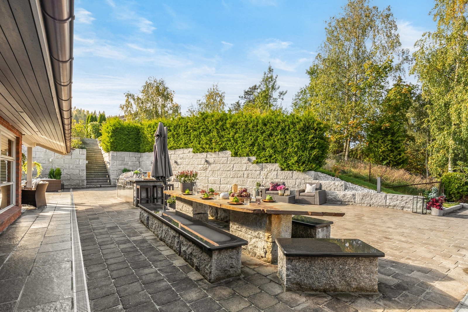 Med belegningsstein, flislagte arealer, frodige plener og store stablemurer i granitt, er det lagt ned stor omsorg for å skape et vakkert og funksjonelt utendørsrom Galleribilde