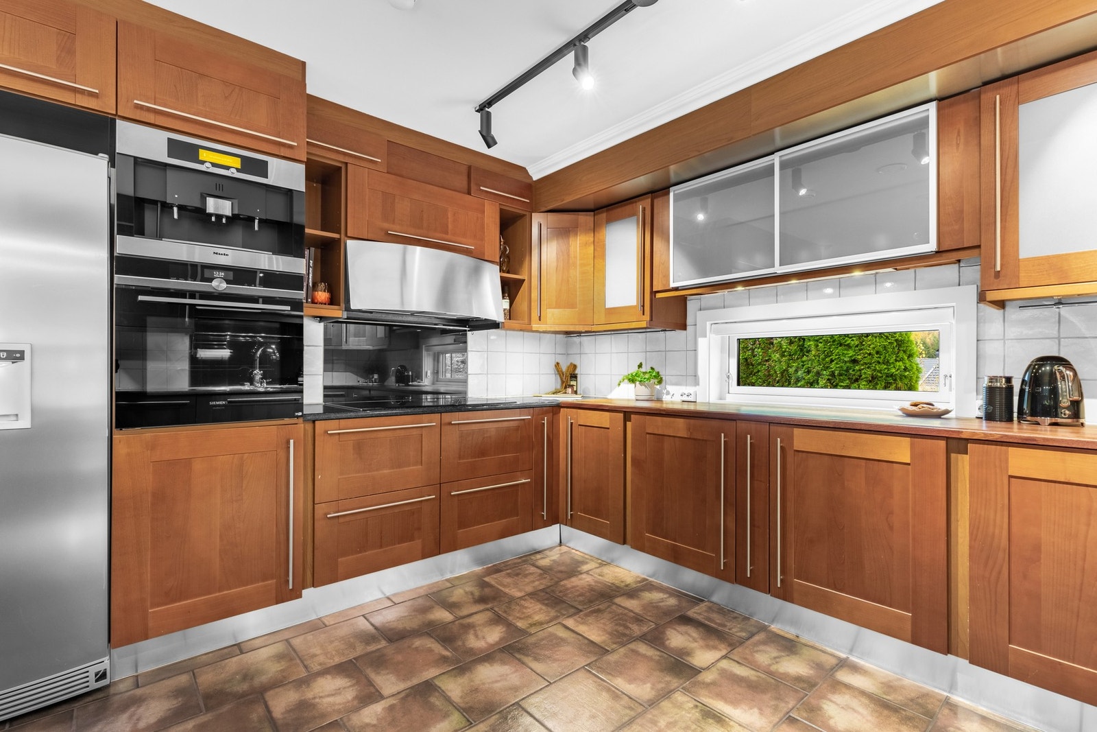 Kjøkkenet inneholder integrerte hvitevarer som induksjonsplatetopp, stekeovn, oppvaskmaskin og kjøl/fryseskap Galleribilde