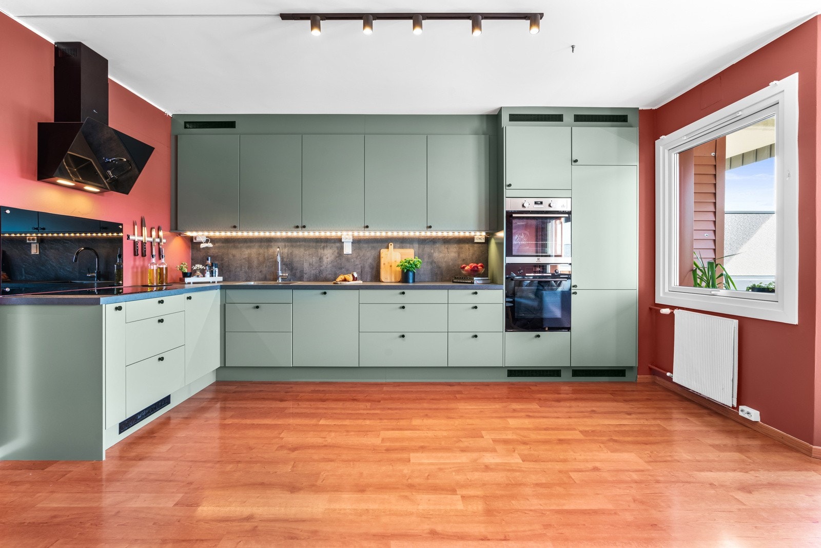 Kjøkkenet fikk ny, stilren innredning i 2022, plassert i en romslig L-form, i åpen løsning med stuen. Den takhøye innredningen fra Epoq har glatte, grønne fronter. Galleribilde