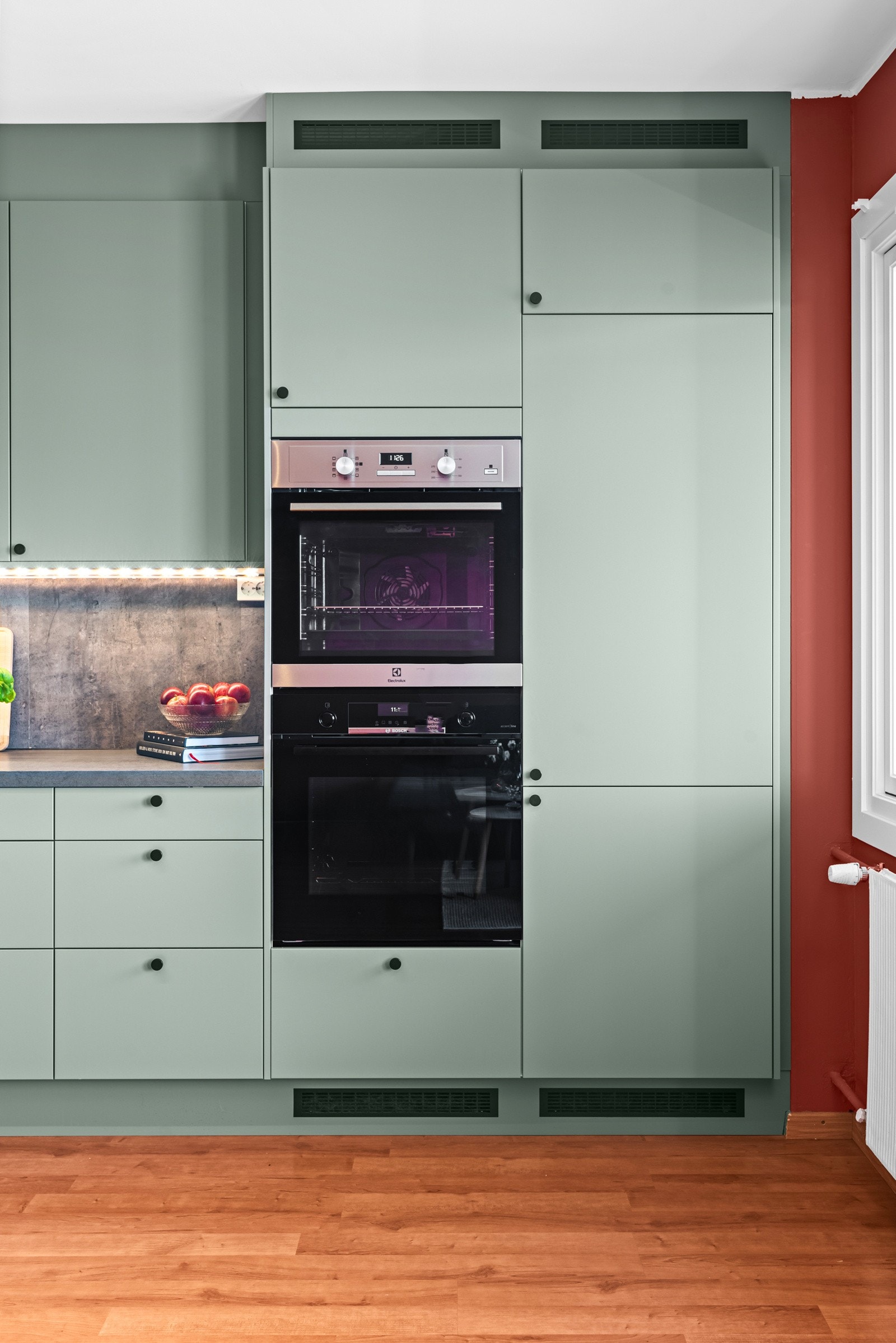 Kjøkkenet har integrert platetopp, to stekeovner (ene med dampfunksjon), oppvaskmaskin og kjøl/frys, samt sort kullfilterventilator med glassfront og sort backsplash i glass over kokesonen. Galleribilde