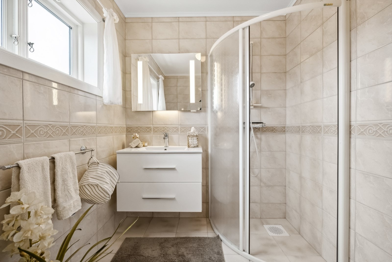 Badet er utstyrt med toalett, dusjhjørne og innredning med skuffer og overliggende servant. Galleribilde