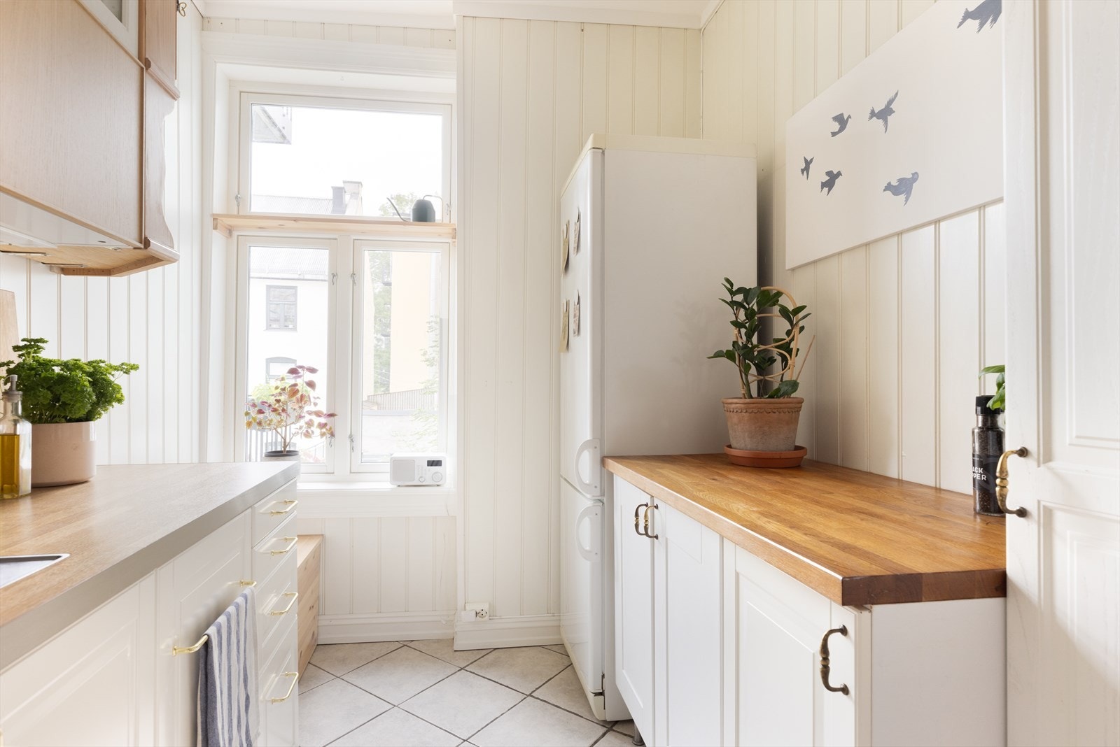 Kjøkkeninnredningen har hvite, profilerte skapfronter i underskap, og glatte fronter i overskap i tillegg til skap med glassfelt. Galleribilde