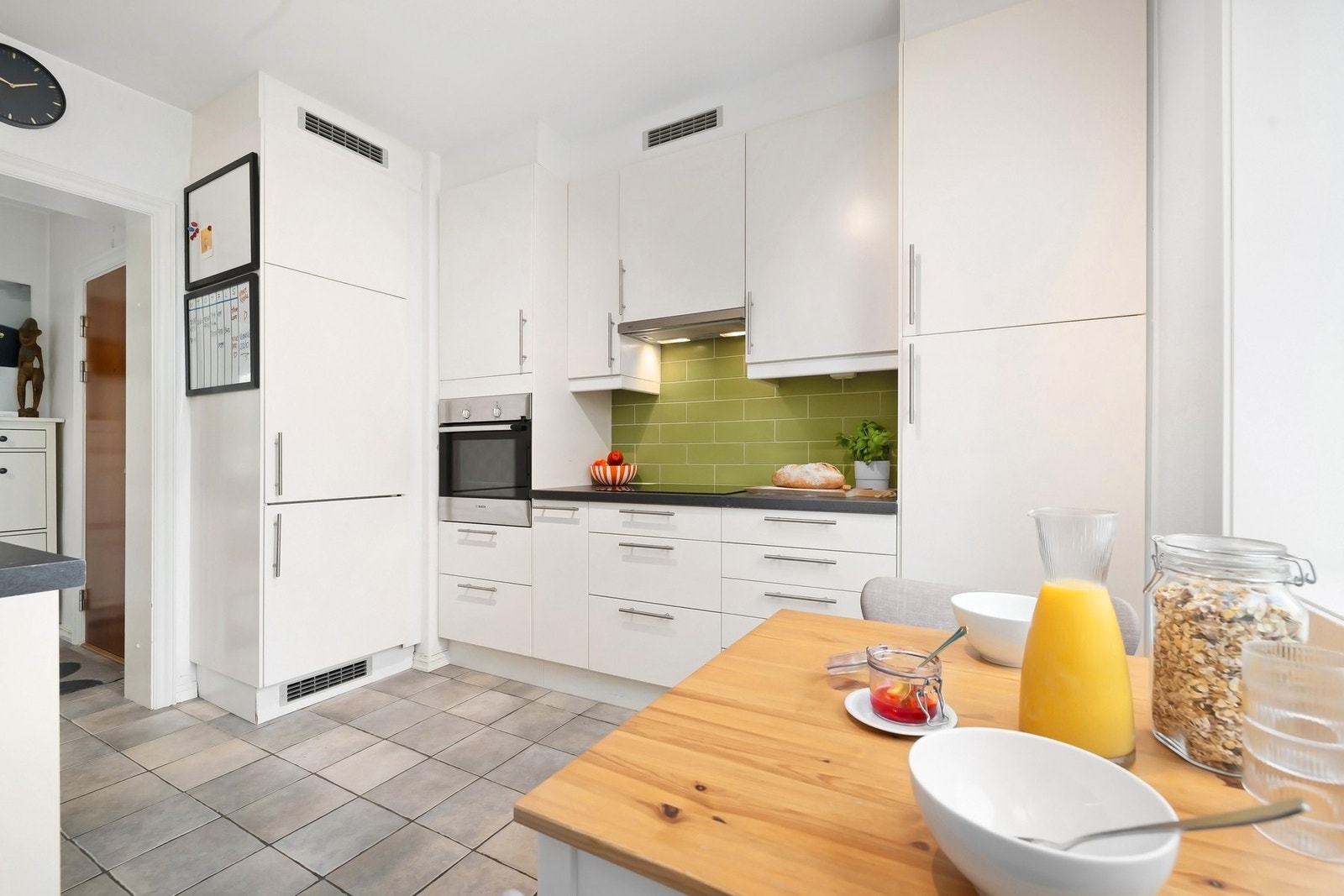 Kjøkken med benke- og overskap med slette fronter, benkeplate av laminat og fliser på vegg over benk Galleribilde