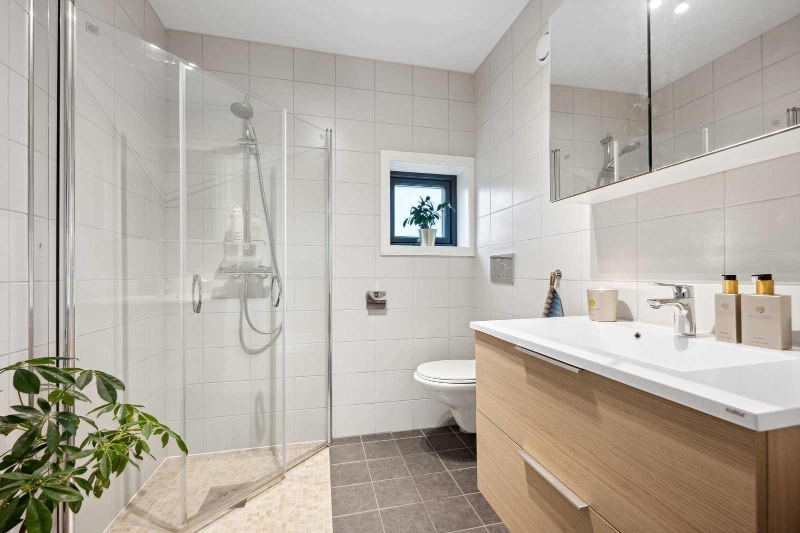 Delikat og flislagt bad I har dusj med glassvegger, wc og baderomsinnredning med speilskap. Galleribilde