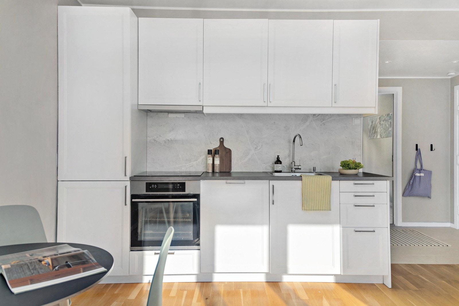 Stilrent kjøkken med integrerte hvitevarer og en lekker backsplash mellom over-og underskap Galleribilde