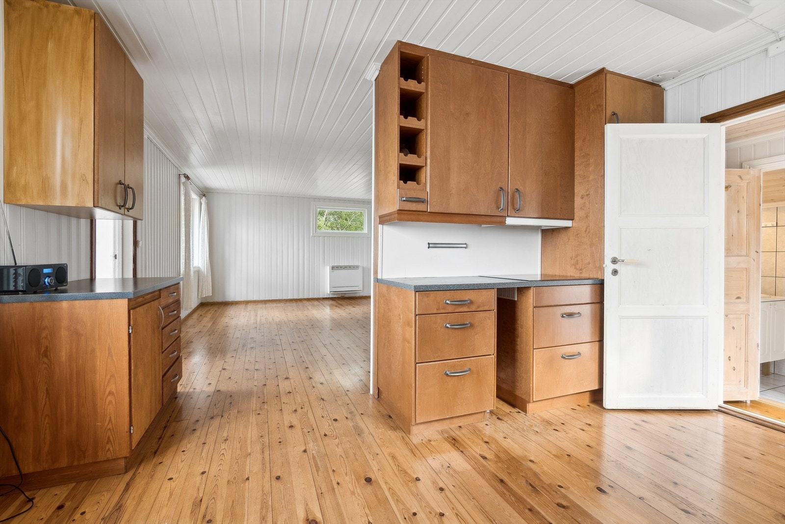 Kjøkkenet ligger i delvis åpen løsning - Innredningen består av slette fronter og benkeplate med nedfelt kjøkkenvask Galleribilde