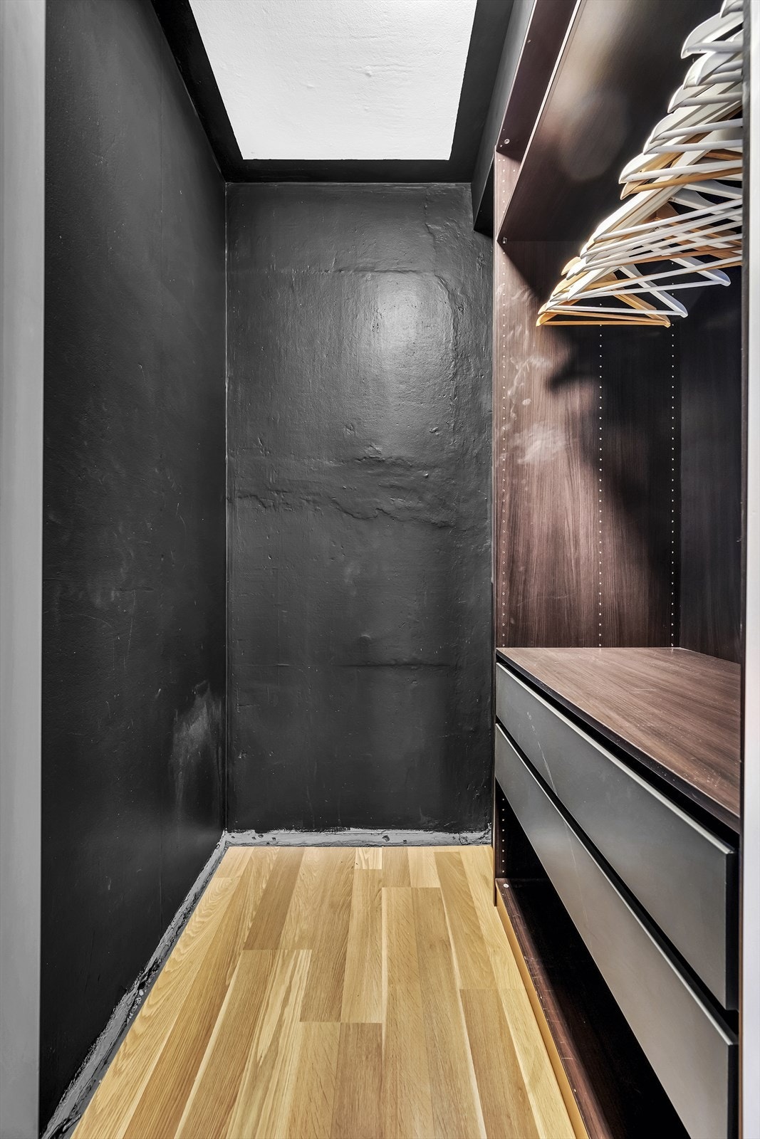 Omkledningsrommet er innredet med åpen garderobeløsning med garderobestang, hyller og skuffer. Galleribilde