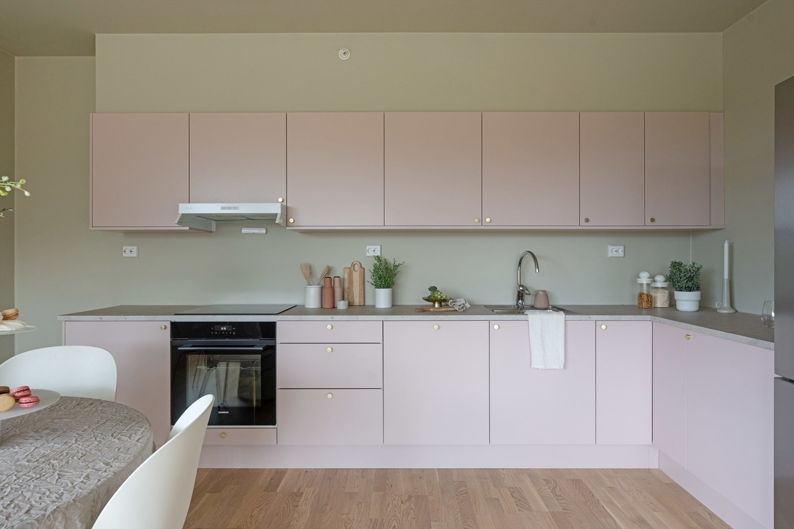 Stilig kjøkken fra Sigdal med hvitevarer fra Siemens. Rosa fronter, gråmelert benkeplate og detaljer i gull. Galleribilde