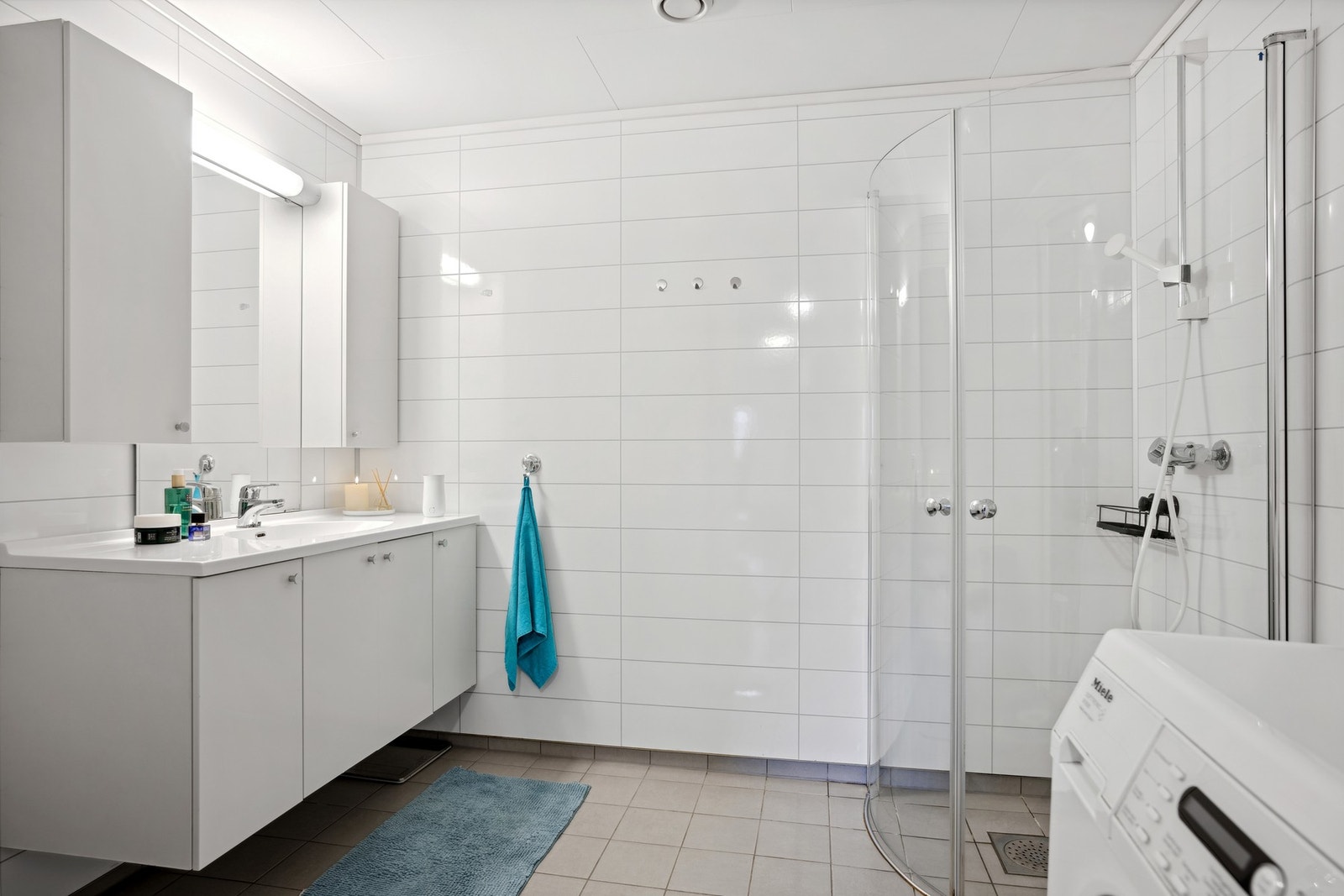 Pent bad/vaskerom utstyrt med baderomsinnredning, dusjplass, toalett og opplegg for vaskemaskin Galleribilde