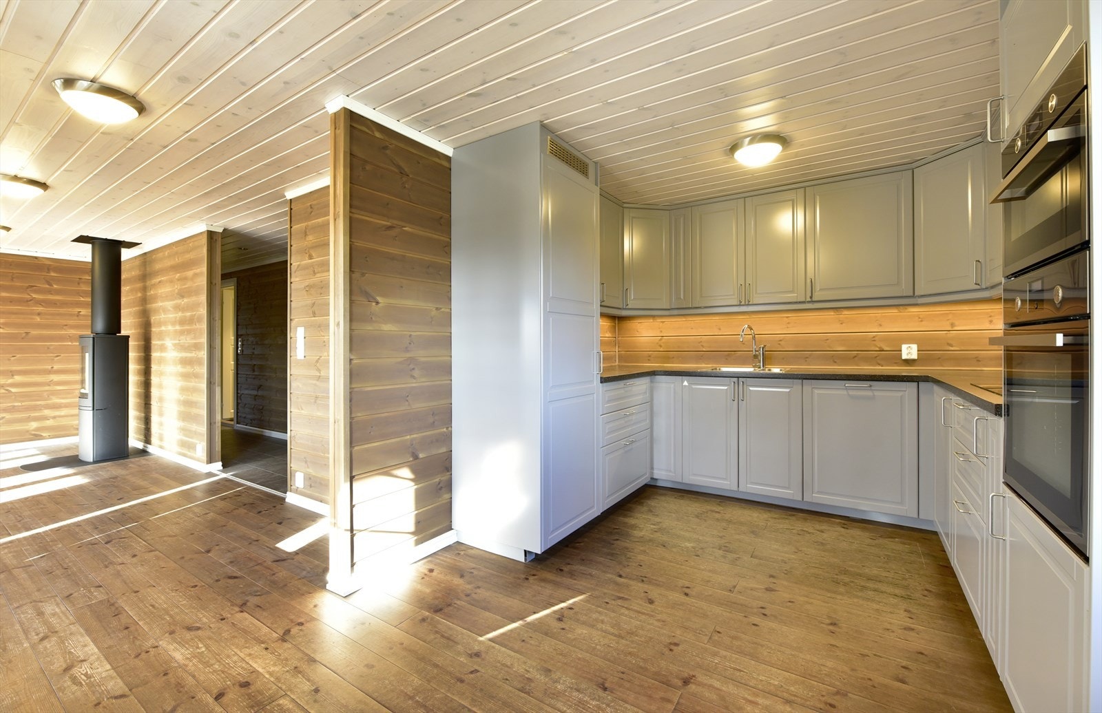 Kjøkken i hoveddel. U-formet innredning med profilerte fronter og integrerte hvitevarer Galleribilde