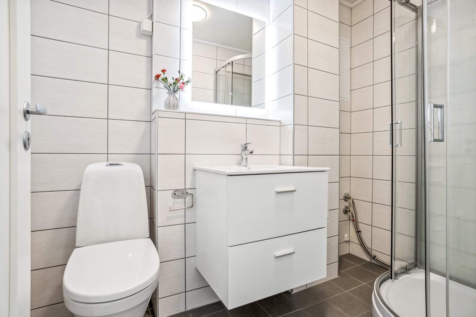 Pent og klassisk bad fra 2022. Badet inneholder toalett, vask med skapinnredning, og dusjkabinett. Galleribilde