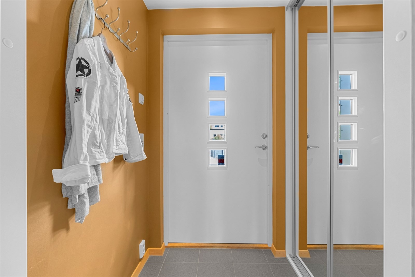 Innenfor ytterdøren møtes man av en entré med skyvedørsgarderobe, flislagt gulv og vegger malt i en frisk farge. Galleribilde