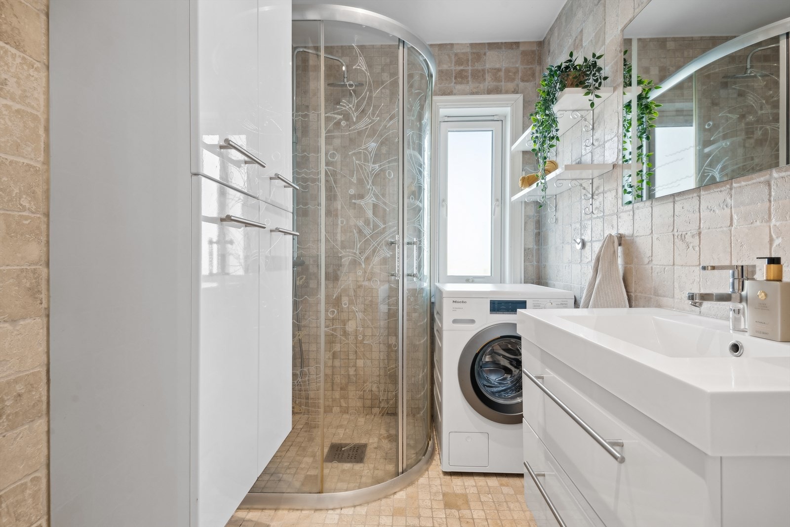 Pent helfliset bad. Varme i gulv. Rommet har innredning med nedfelt servant, toalett, dusjvegger/hjørne og opplegg for vaskemaskin. Galleribilde