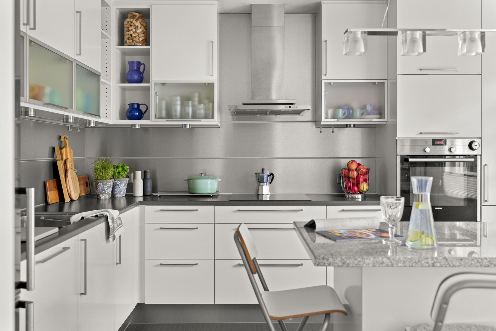 Innredningen har hvite, glatte fronter og grå laminatbenkeplate med planlimt kum i stål. Galleribilde