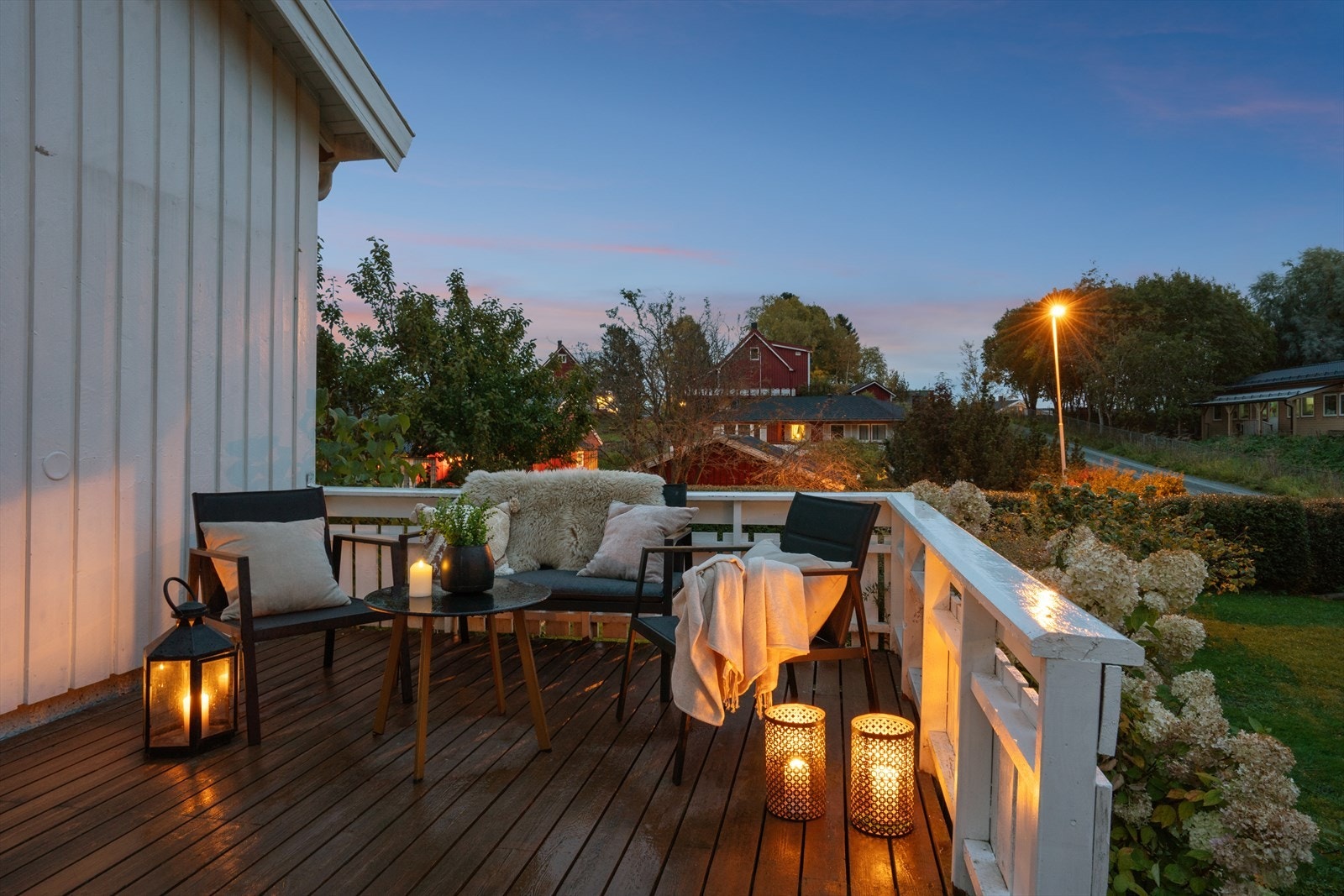 Veranda utenfor stuen har tredekke, hvitmalt rekkverk og trapp ned til hagen. Galleribilde