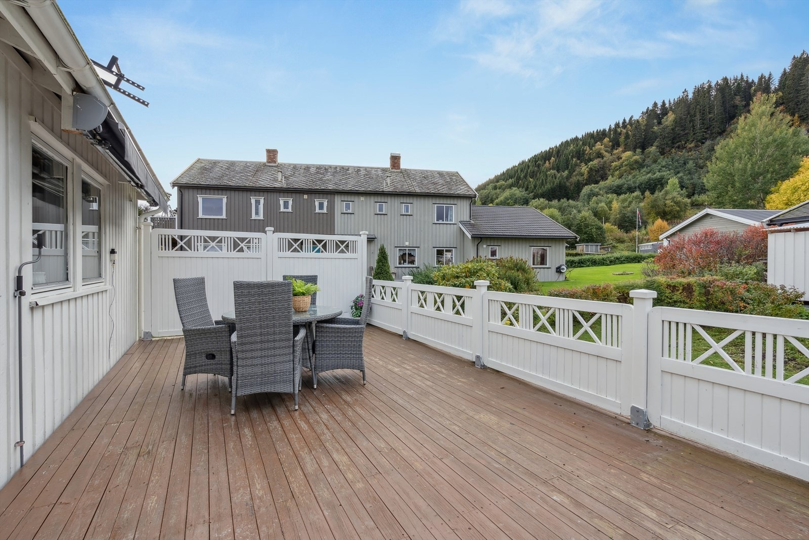 Terrassen ved inngangspartiet har tredekke, hvitmalt rekkverk og skjermende levegg i ene enden. Galleribilde